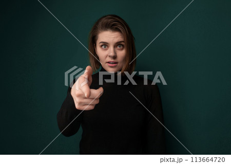 Woman Pointing at Camera on Green Background 113664720