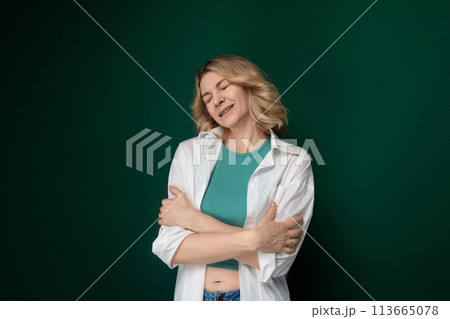 Woman Standing With Crossed Arms in Front of Green Wall 113665078