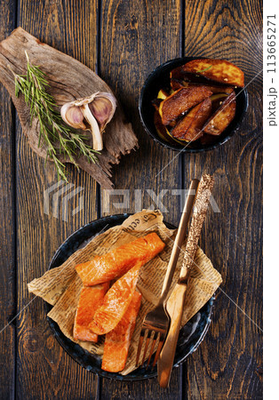pieces of battered fish on a plate with baked potato on a wooden table with space pieces of battered fish on a plate with baked potato on a wooden table with space 113665271