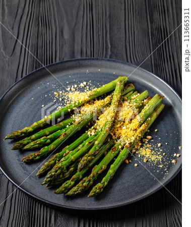 roasted asparagus with nut yeast crumble on plate 113665311