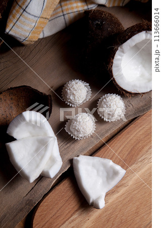 Coconut with white pulp and white candies on wooden background.. Coconut with white pulp and white candies on wooden background.. 113666014