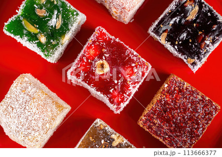 Colorful traditional oriental sweets Turkish delight (rahat locum) closeup on a red background. 113666377