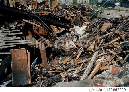 A burnt-out old wooden building after a fire. Charred beams after the destruction. 113667060