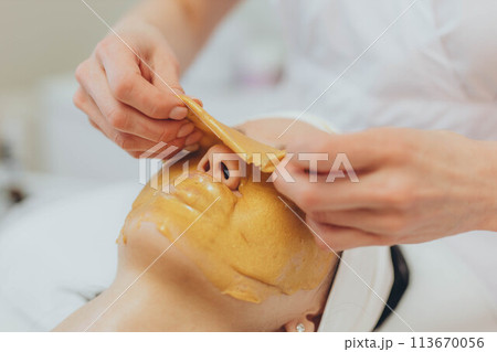 A girl at a cosmetologist does cosmetic procedures. Alginate mask 113670056