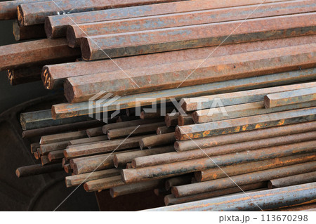 A pile of rusty metal rods. The rods are stacked on top of each other and are all different sizes 113670298