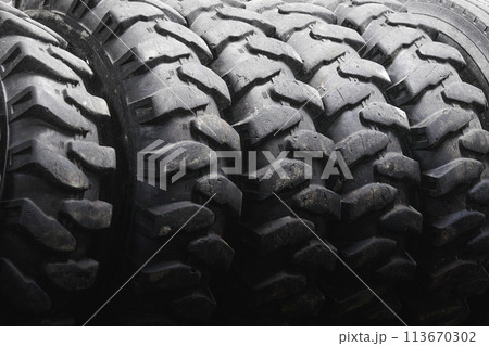 A close up of a tire with a black rim. The tire is black and has a lot of tread 113670302