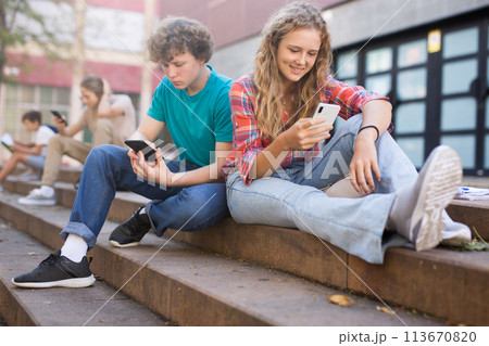 Teenagers with smartphones sitting on stairs Teenagers with smartphones sitting on stairs 113670820
