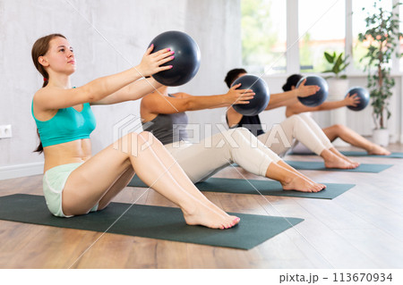 Women and man maintaining physical health practicing pilates with fit balls at group workout 113670934