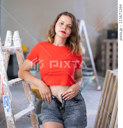 Sexy young woman in a red t-shirt posing next to a stepladder in renovated room Sexy young woman in a red t-shirt posing next to a stepladder in renovated room 113671264