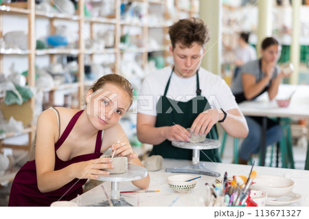 Pottery lesson - teenagers girl and guy intently create dishes from clay 113671327