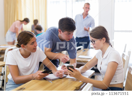 Students wih phones solving teacher assignments in groups Students wih phones solving teacher assignments in groups 113671551