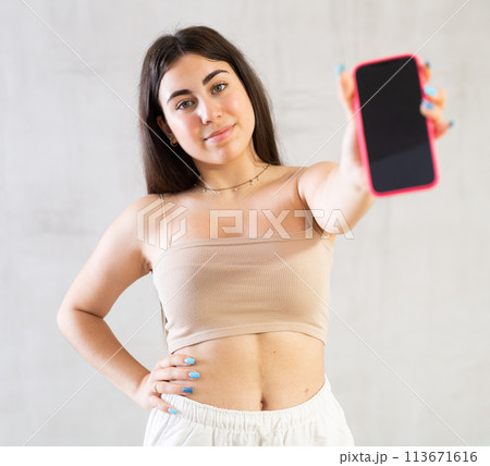 Young smiling woman posing with phone in studio Young smiling woman posing with phone in studio 113671616