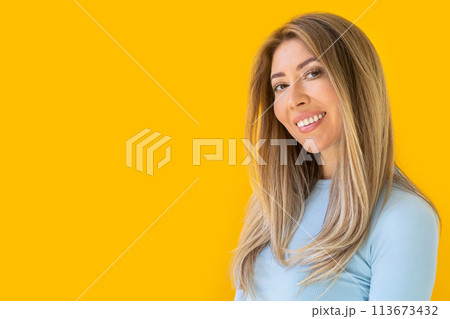 Portrait of a young Caucasian woman with pleasant smile isolated on yellow wall with copy space.  113673432