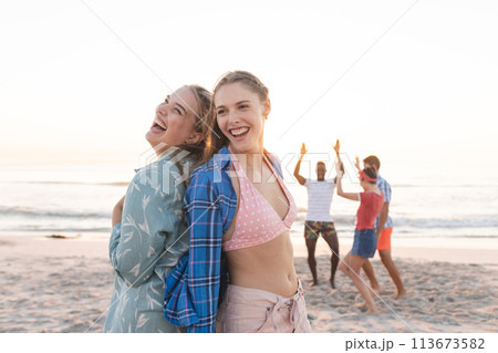 Friends enjoy a vibrant beach sunset, with copy space Friends enjoy a vibrant beach sunset, with copy space 113673582