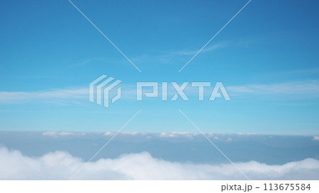Sea of clouds view from a mountain peak against a background of a blue sky. 113675584