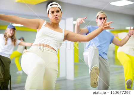Teenage girl having group dance training in studio, performing dynamic elements 113677297