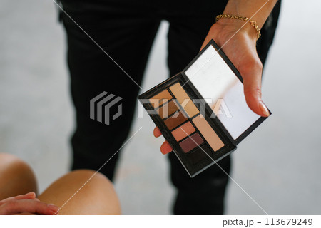 Palette with shadows in the hand of a makeup artist in close-up 113679249