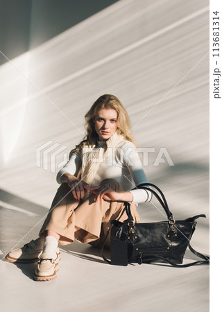 beautiful curly blond hair woman posing with a small shopper bag sitting on the floor beautiful curly blond hair woman posing with a small shopper bag sitting on the floor 113681314