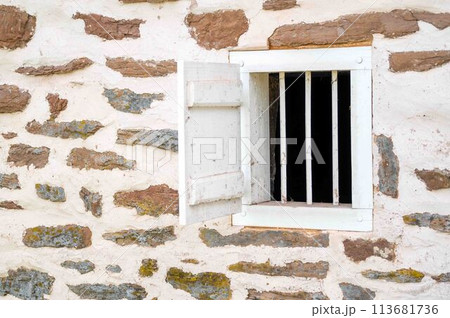 Small ventilation window with bars and shutter colonial farm building 113681736