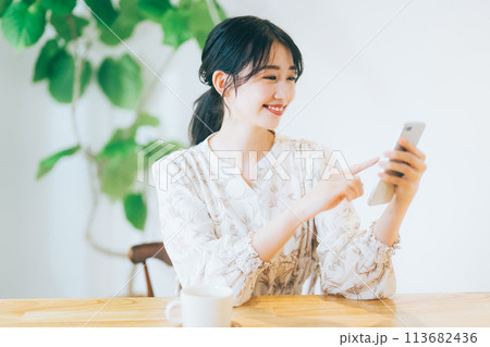 リビングでスマホを見る女性 113682436
