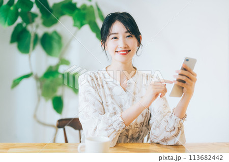 リビングでスマホを見る女性 113682442