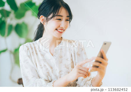 リビングでスマホを見る女性 113682452