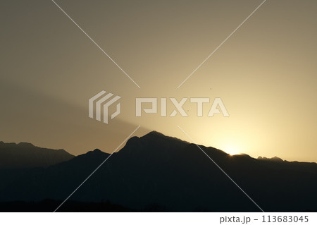 黄砂に染まる南アルプスの山並みに沈む夕日 113683045