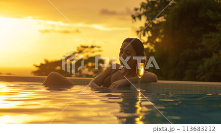 A close-up portrait of a woman against the cool stone edge of a pool, with a vibrant mocktail  113683212