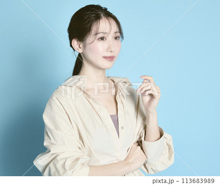 青背景で撮影した若い女性のポートレート 113683989