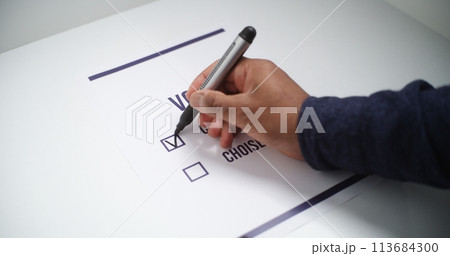 Close up of anonymous male voter filling out paper ballot during elections 113684300