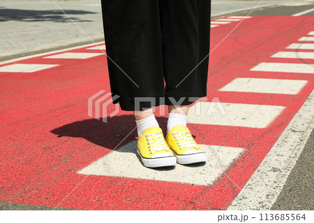 Stylish yellow sneakers on women's legs on the asphalt 113685564