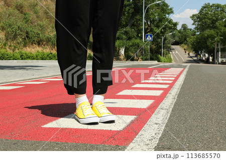 Stylish yellow sneakers on women's legs on the asphalt 113685570