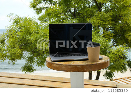 Laptop on table with coffee overlooking the sea 113685580