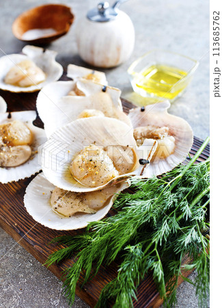 From above fresh appetizing scallop with shell served on wooden boars From above fresh appetizing scallop with shell served on wooden boars 113685762