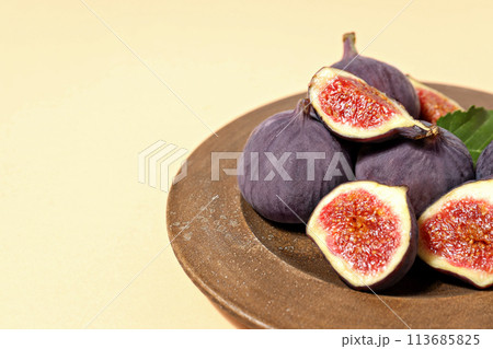 Fresh ripe figs in a wooden bowl on a light background 113685825