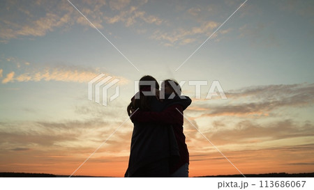 Girls friends hugging at sunset in park, silhouettes. Happy smiling girls women acquaintance friends girlfriends hugging embracing cuddling at sunset dawn sky clouds. Nice meeting, close relationship 113686067
