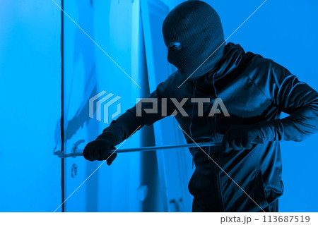 Intruder using crowbar on a door at night Intruder using crowbar on a door at night 113687519
