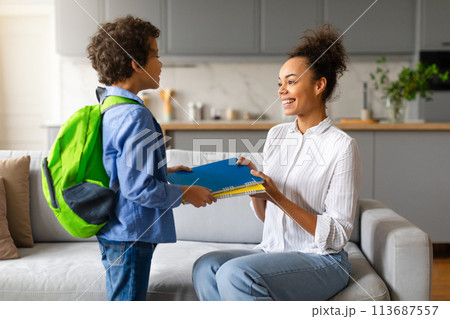 Son taking school items from mother 113687557