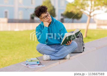 Student with book contemplates on campus Student with book contemplates on campus 113687569