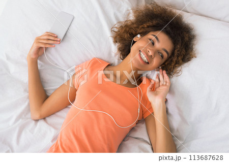 Young woman resting in bed with smartphone 113687628