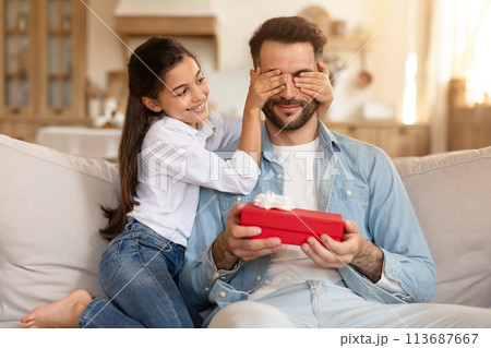 Daughter covering father's eyes, gift in her hand 113687667