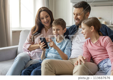 Family interacting with smartphone together at home Family interacting with smartphone together at home 113687676