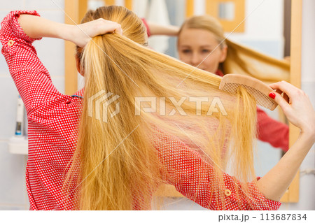 Woman combing her long hair in bathroom Woman combing her long hair in bathroom 113687834