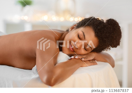 Woman smiling on massage table at spa Woman smiling on massage table at spa 113687837