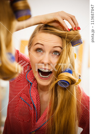 Woman curling her hair using rollers Woman curling her hair using rollers 113687847