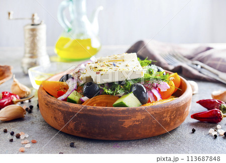 Greek salad of fresh cucumber, tomato, sweet pepper, lettuce, red onion, feta cheese and olives with olive oil. Healthy food, top view Greek salad of fresh cucumber, tomato, sweet pepper, lettuce, red onion, feta cheese and olives with olive oil. Healthy food, top view 113687848