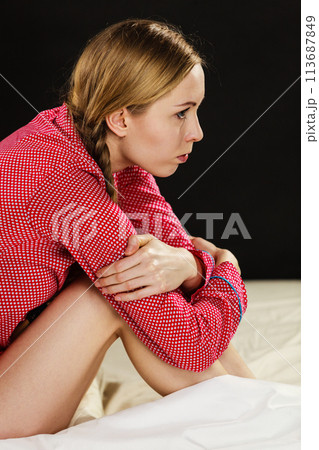 Sad young teenager woman sitting on bed Sad young teenager woman sitting on bed 113687849