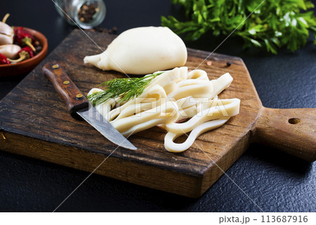 Boiled calamari squid rings on wooden board, cooked squid on cutting rings on board. 113687916