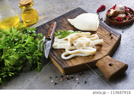 Boiled calamari squid rings on wooden board, cooked squid on cutting rings on board. 113687918