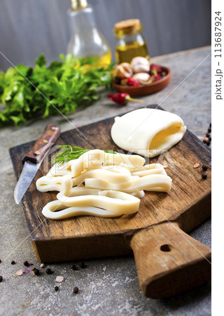 Boiled calamari squid rings on wooden board, cooked squid on cutting rings on board. Boiled calamari squid rings on wooden board, cooked squid on cutting rings on board. 113687924